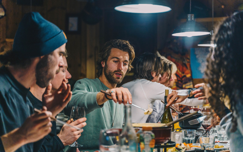 En gruppe venner sidder og nyder fondue på restaurant i Alperne