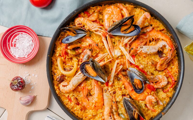 Paella er en traditionel spansk risret, typisk tilberedt med safran, forskellige kød, skaldyr og grøntsager, og serveres i en bred, lav pande