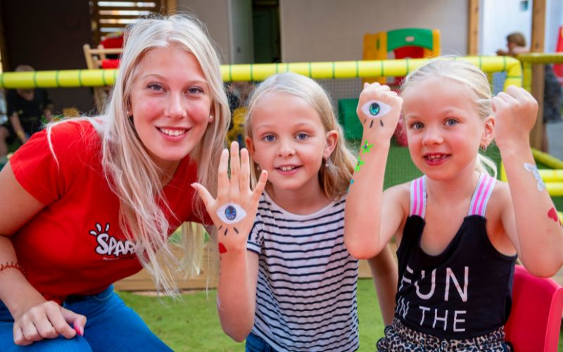 Piger med maling på hænderne smiler i kids club på et hotel